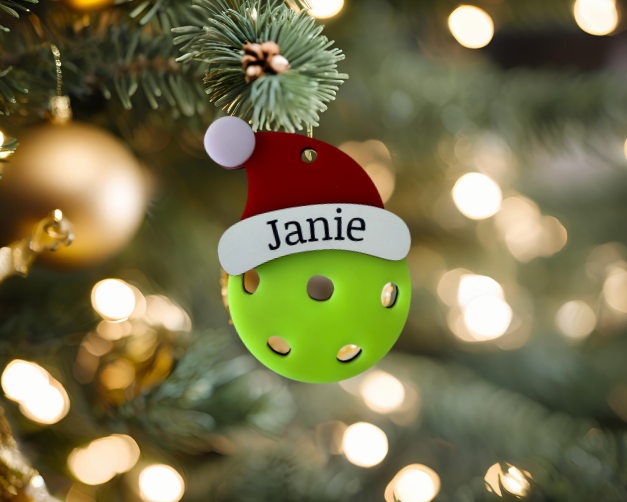 Pickleball ornament with a red and white hat, personalized with 'Janie', on a Christmas tree.