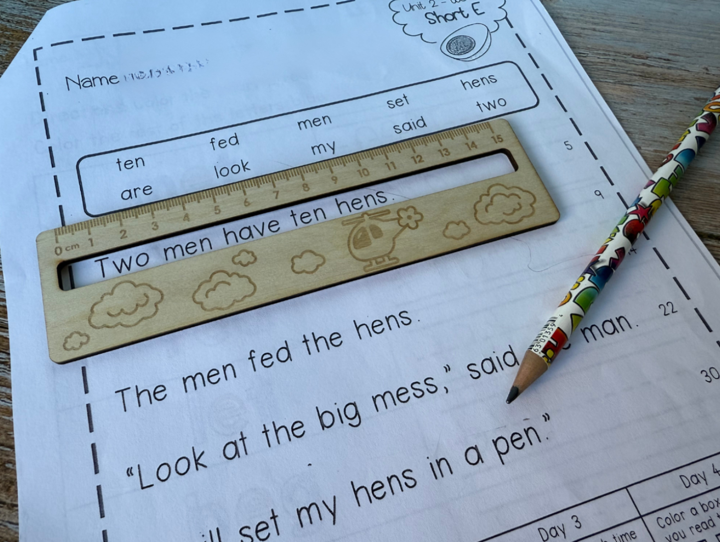 Wooden ruler with cloud design on a worksheet with text and a pencil.